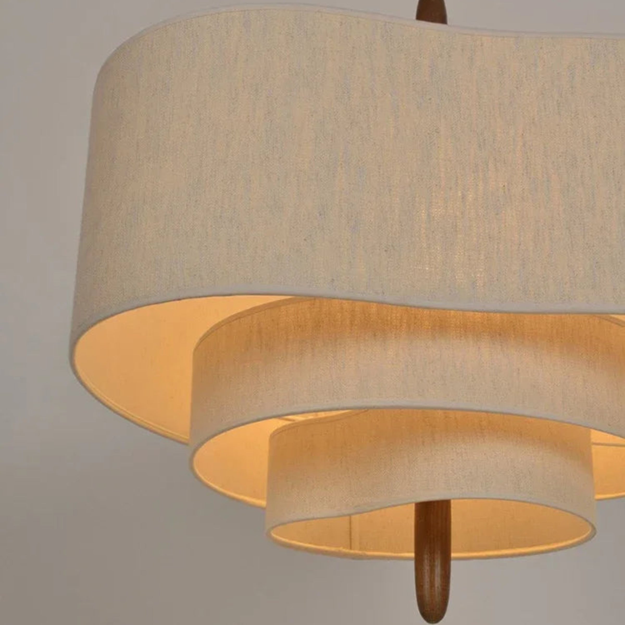 Two-layered pendant lamp with beige fabric shades on a plain background