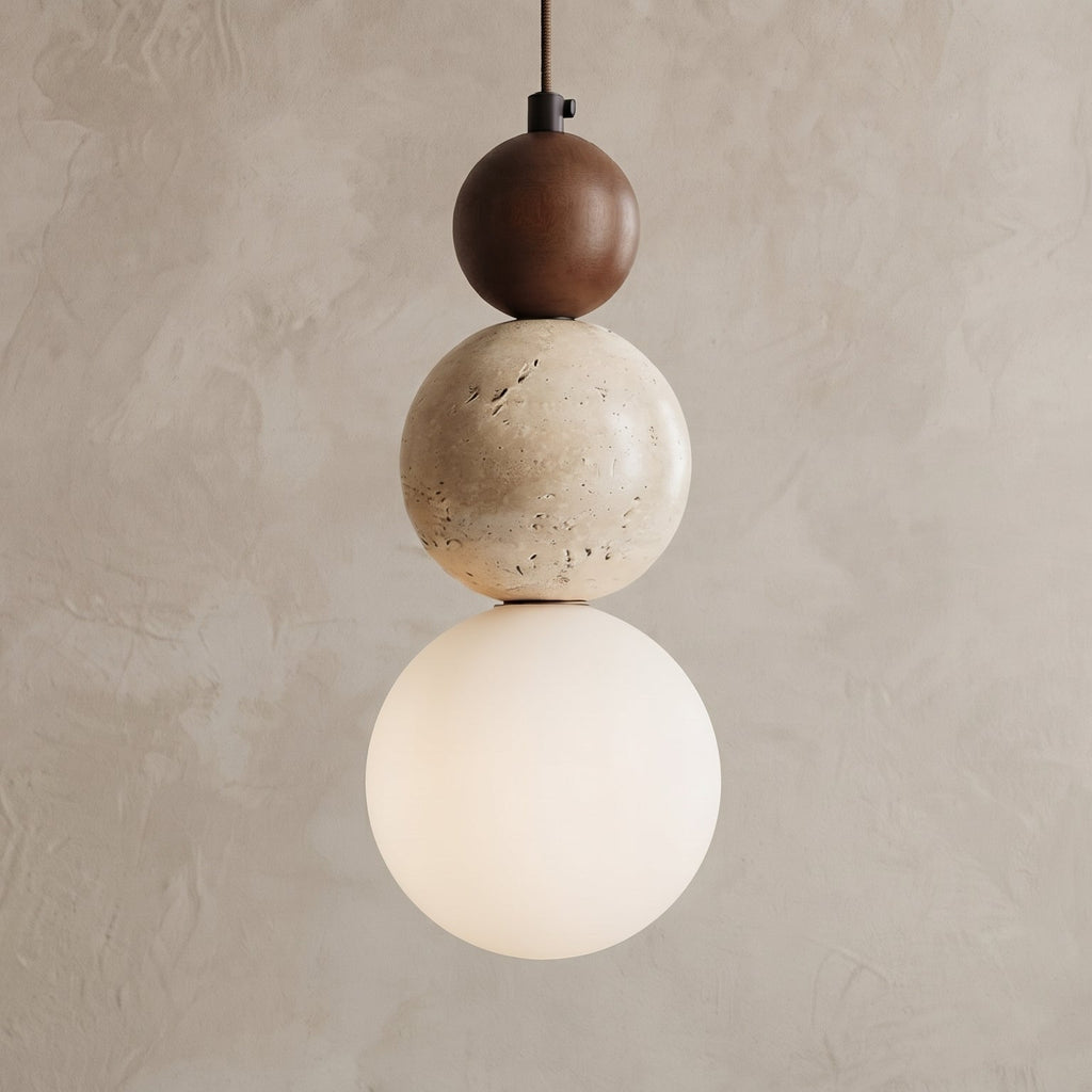 A modern three-sphere pendant light hanging against a textured beige plaster wall. The light features a dark brown top sphere, a speckled cream middle sphere, and a glowing warm white bottom globe shade.