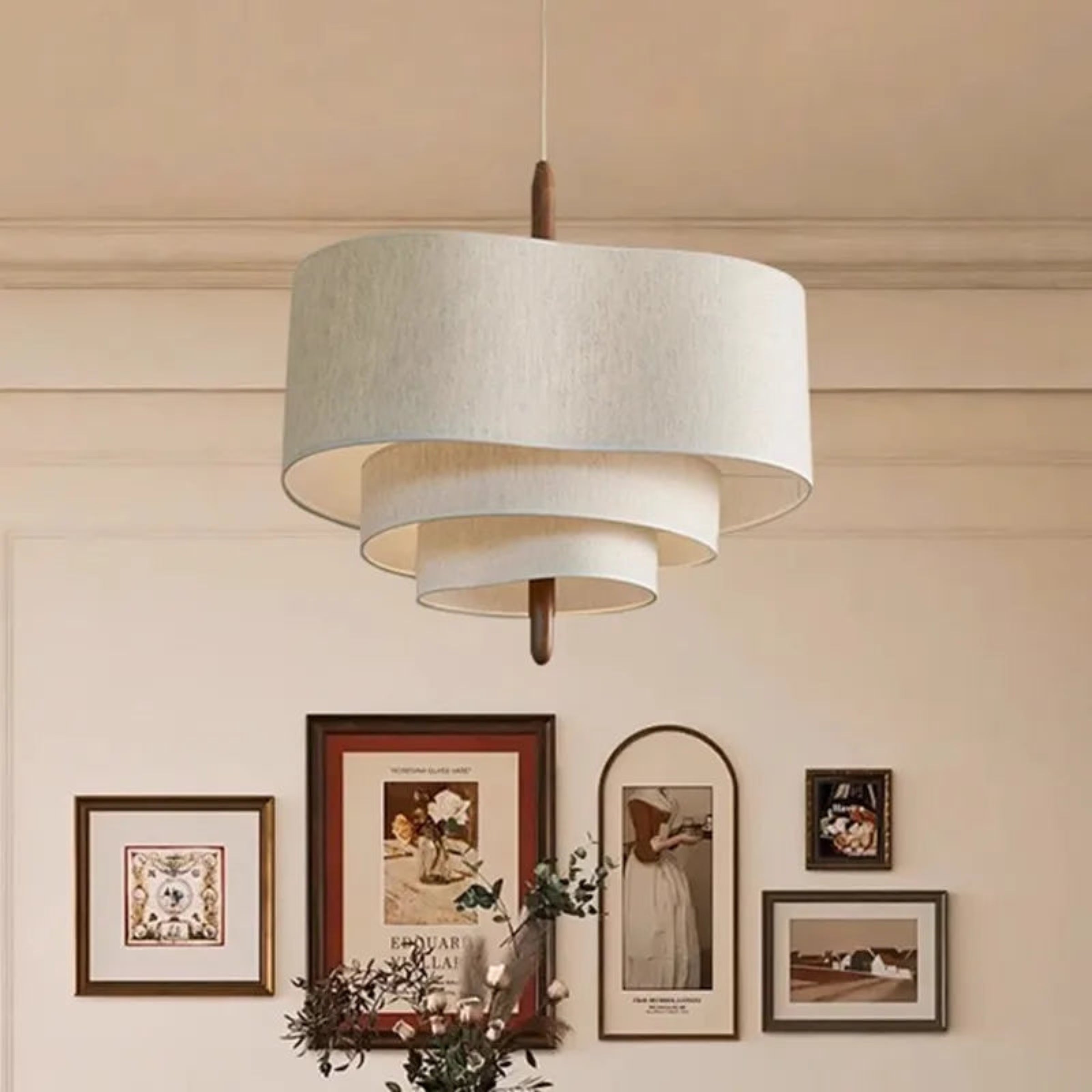 Ceiling light fixture with a neutral shade in a room with framed pictures on the wall.