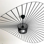 Ceiling light fixture with black metal sunburst design on a white ceiling