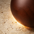 Decorative sphere made of travertine stone and hand-polished wood on a textured surface with text highlighting natural materials.