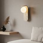 Wall-mounted light fixture with a textured concrete-like finish on a plain background