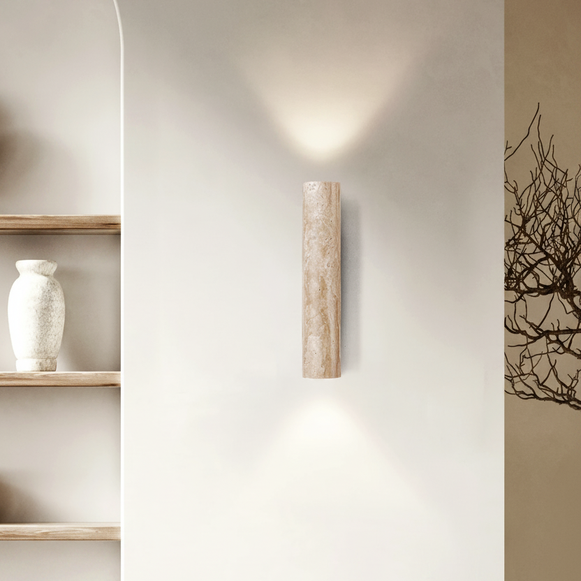 Wall-mounted cylindrical light fixture on a neutral wall with shelves and decor.