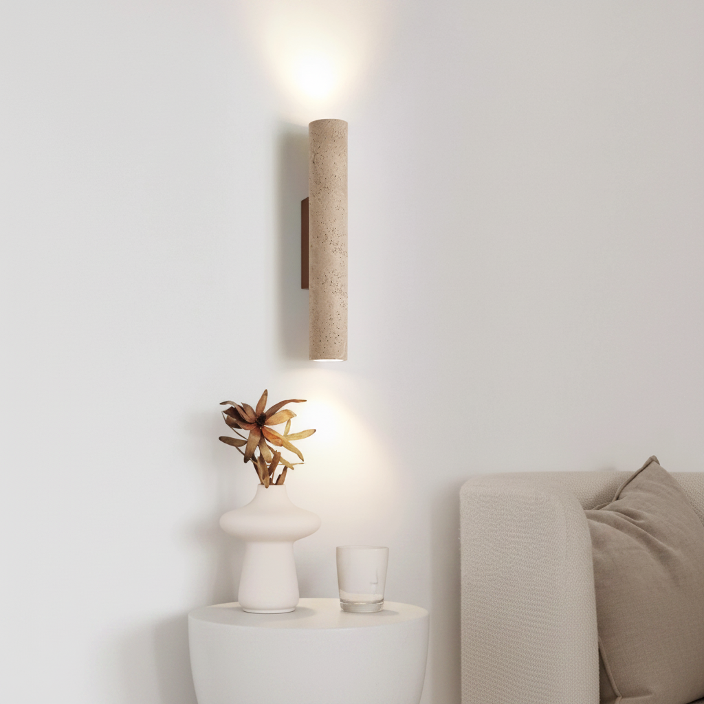 Cylindrical wall light fixture on a white wall with a minimalistic interior setting.