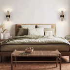 Modern bedroom with a bed, side tables, and wall sconces.