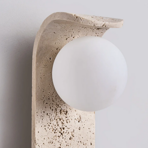 Decorative wall sconce with a textured stone-like finish and a white globe light.