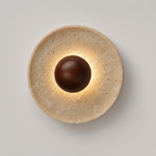 Round wall light fixture with a brown central bulb on a neutral background