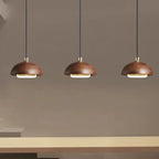Three brown pendant lights hanging above a table against a gray wall.