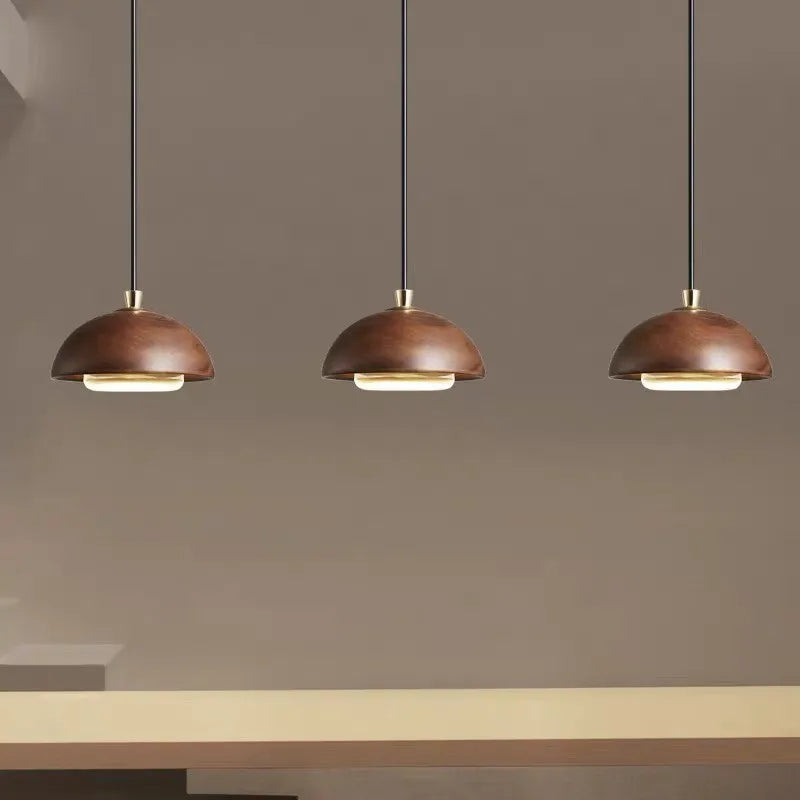 Three brown pendant lights hanging above a table against a gray wall.