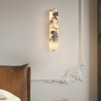 Wall-mounted light fixture in a bedroom setting with a bed and decorative box.