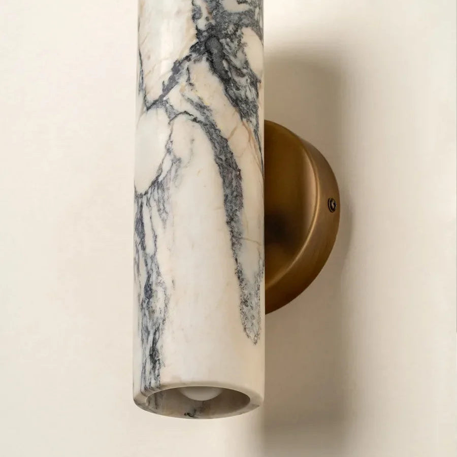 Wall-mounted light fixture with marble-like cylindrical shade on a plain background