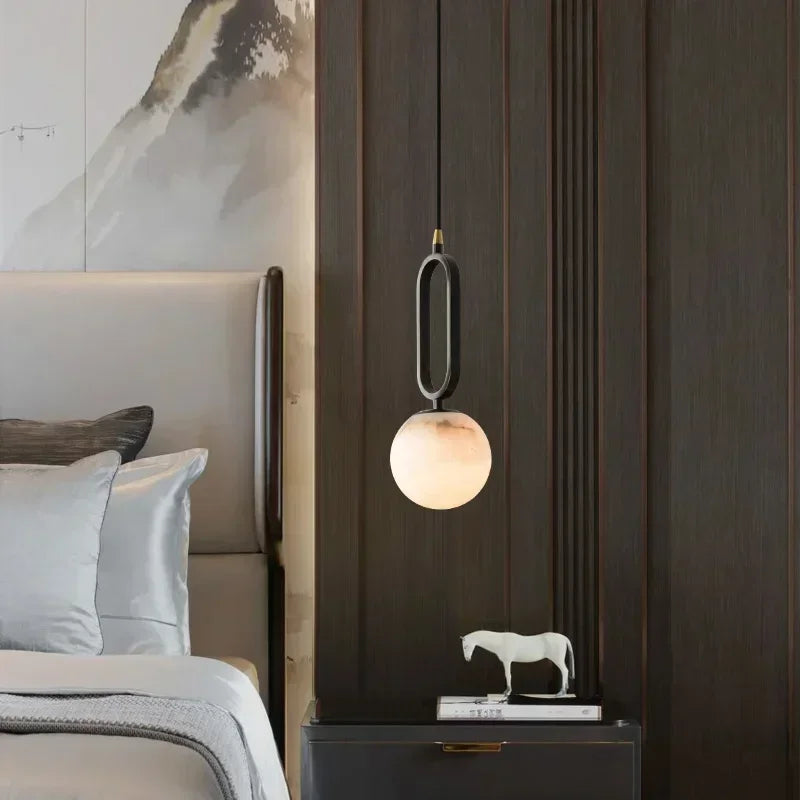 Modern bedroom with a pendant light, bed, and decorative items.