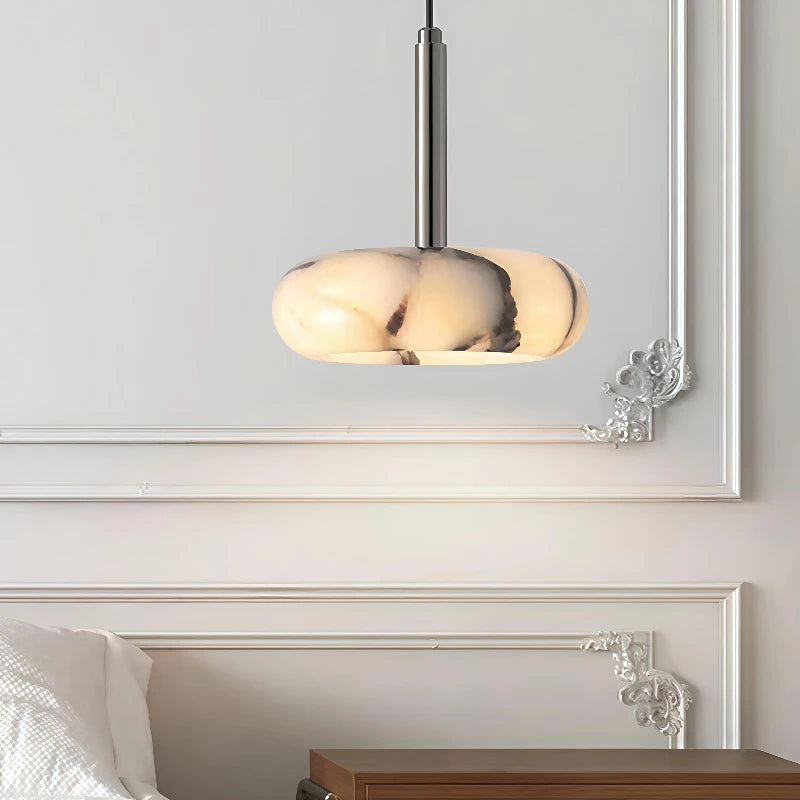 Modern pendant light fixture on a wall above a bed in a bedroom setting.