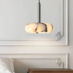 Modern pendant light fixture on a wall above a bed in a bedroom setting.