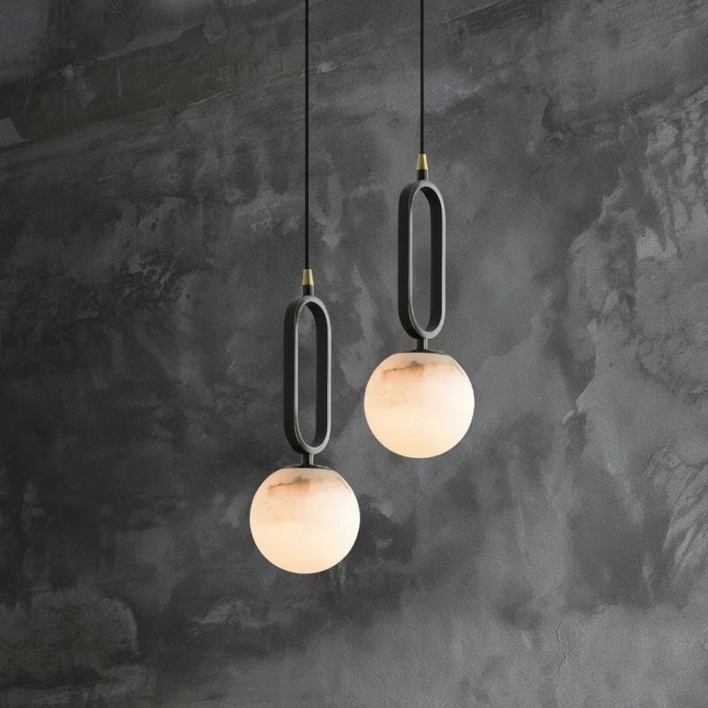 Two modern pendant lights with marble-like finishes hanging against a textured dark wall.