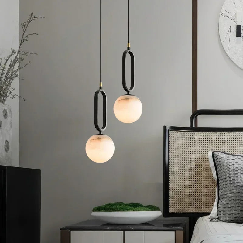 Modern pendant lights hanging above a bed in a bedroom setting.