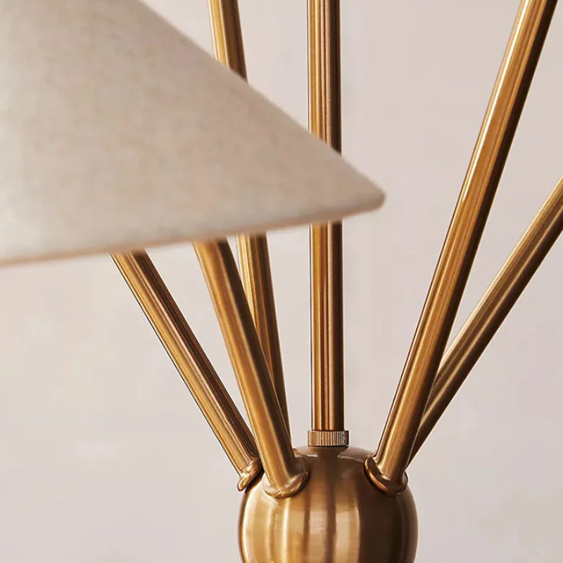 Close-up of a gold floor lamp with a beige lampshade on a neutral background