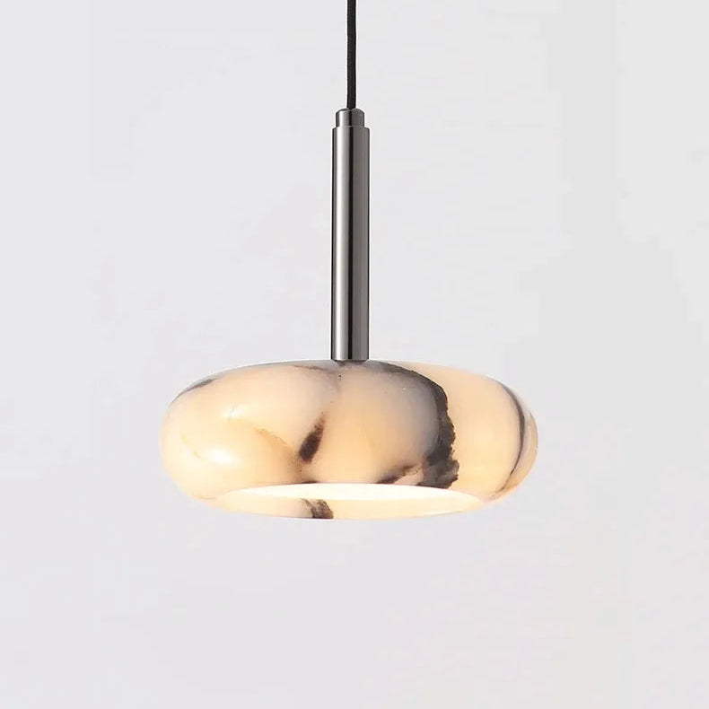 A modern pendant light with a rounded, disc-shaped translucent shade in a cream and black marbled pattern, suspended by a slim vertical metallic rod against a light gray background.