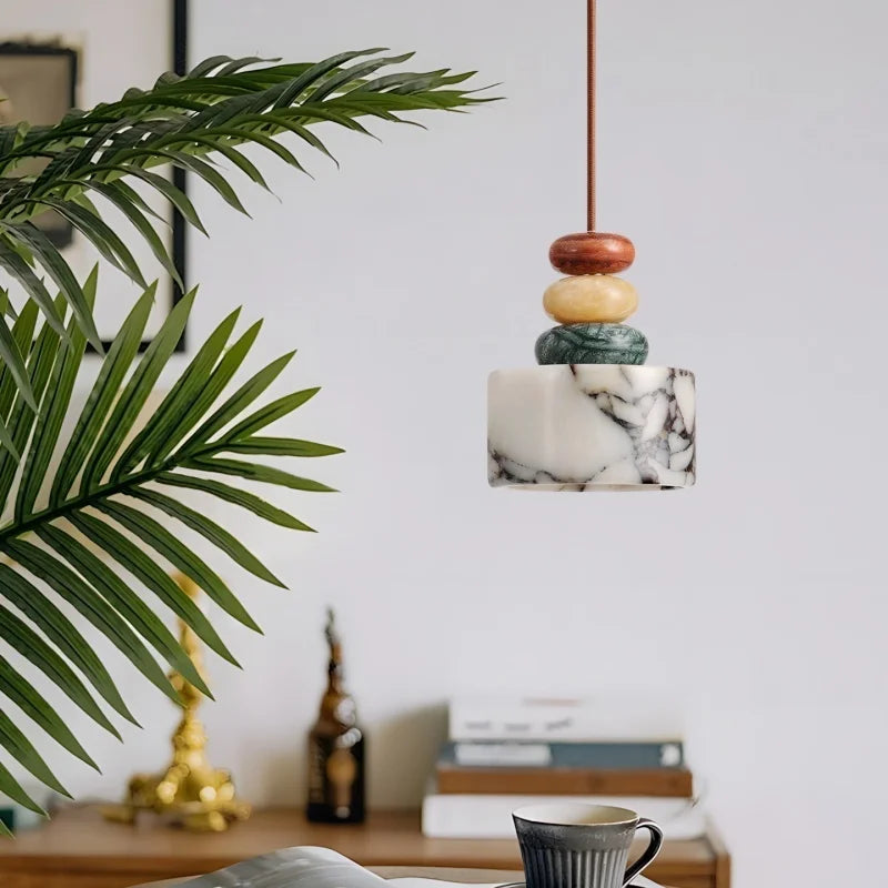 Marble pendant light with wooden accents in a room with a plant and books.