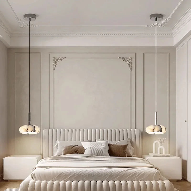 Modern bedroom with a large bed, decorative headboard, and hanging lights.