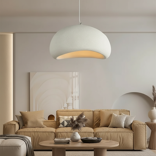 Modern living room with a beige sofa, round pendant light, and decorative elements.