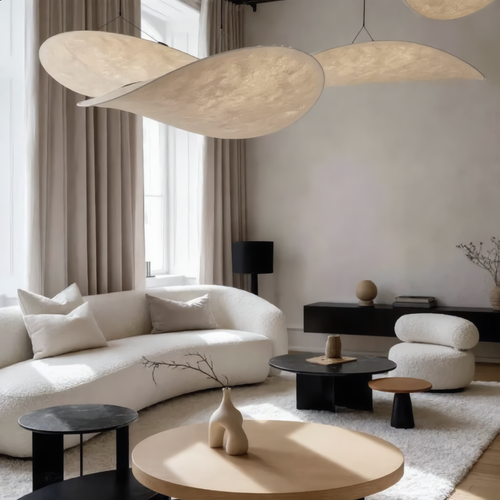 Modern living room with white sofa, round wooden coffee table, and pendant lights.
