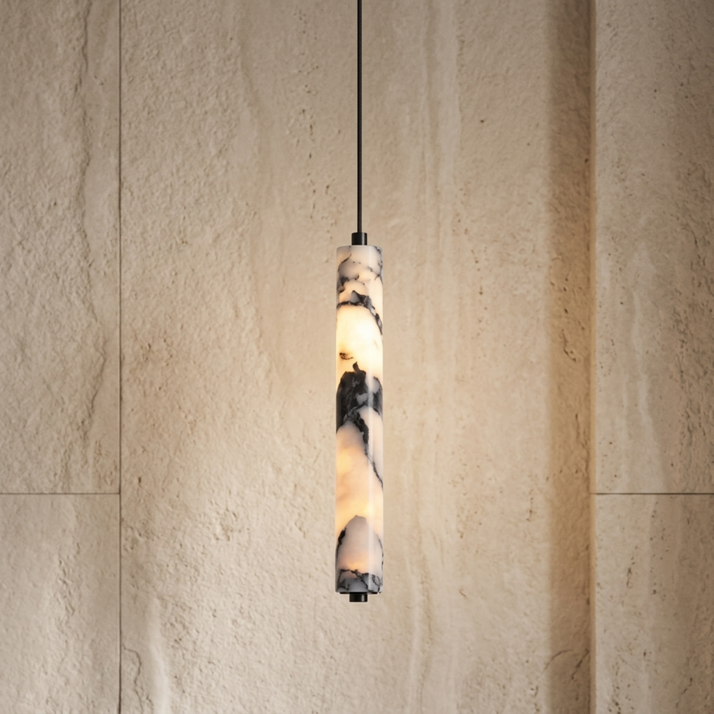 A modern cylindrical pendant light with a marbled stone or resin shade glowing warm white, suspended by a thin black cord against a textured beige stone wall.
