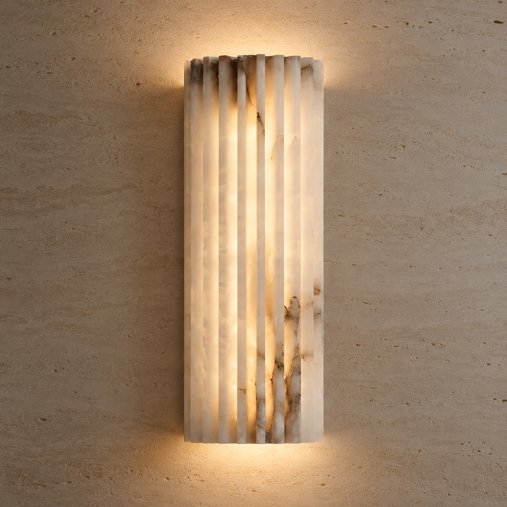A modern vertical rectangular wall sconce made of fluted translucent stone, glowing with warm light against a textured beige plaster wall.