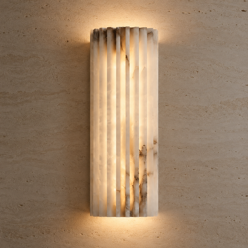 A modern vertical rectangular wall sconce made of fluted translucent stone, glowing with warm light against a textured beige plaster wall.