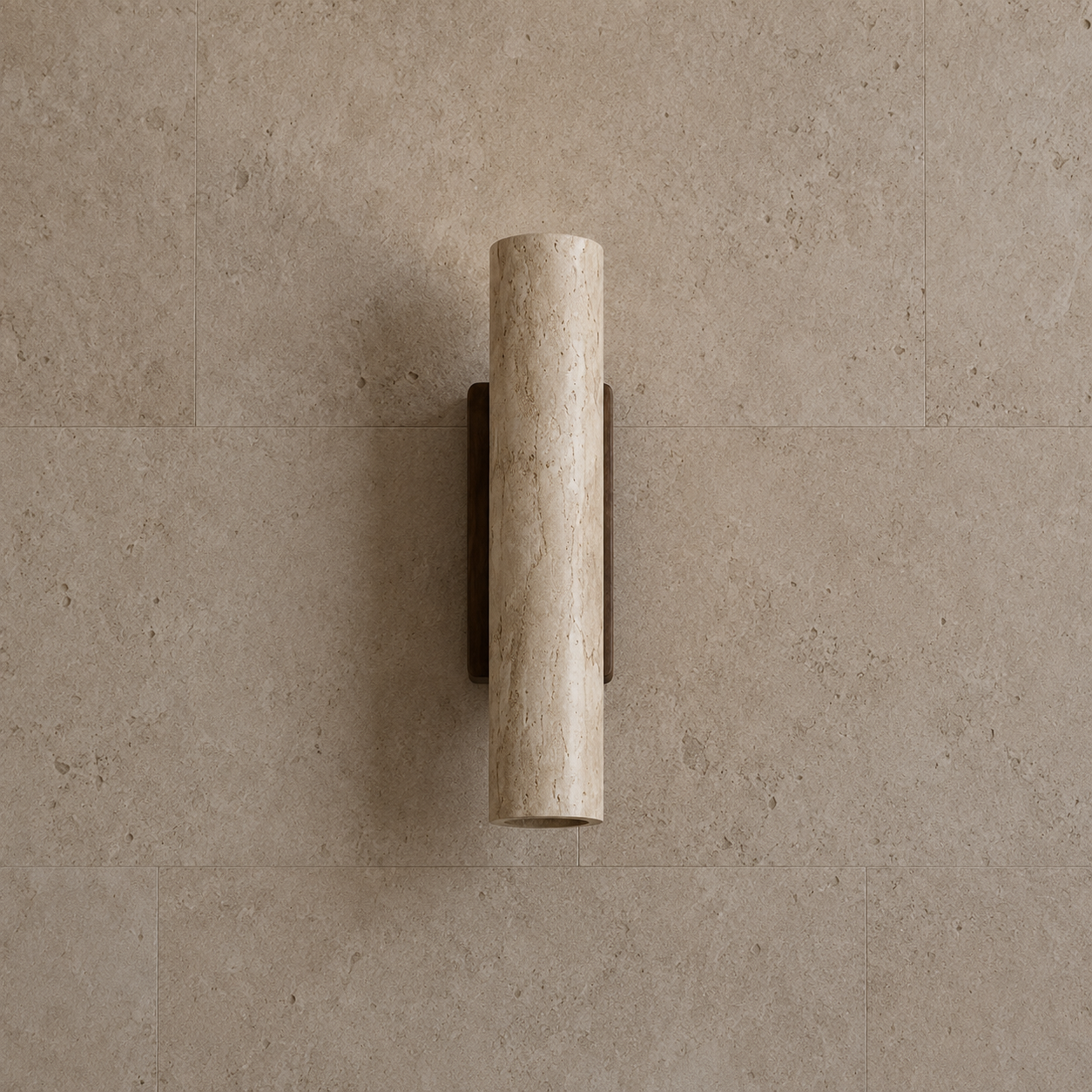 A modern cylindrical wall sconce with a textured beige travertine stone shade and a dark bronze metal mount, shown against a matching beige stone tile wall.