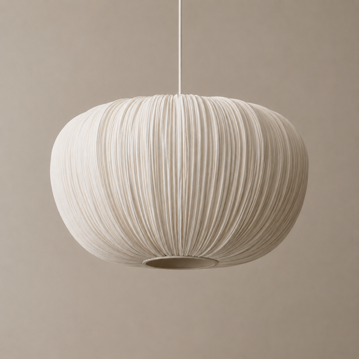 A modern pendant light with a pleated, ribbed fabric shade in a warm off-white or cream color, suspended by a thin cord against a solid, warm beige background.