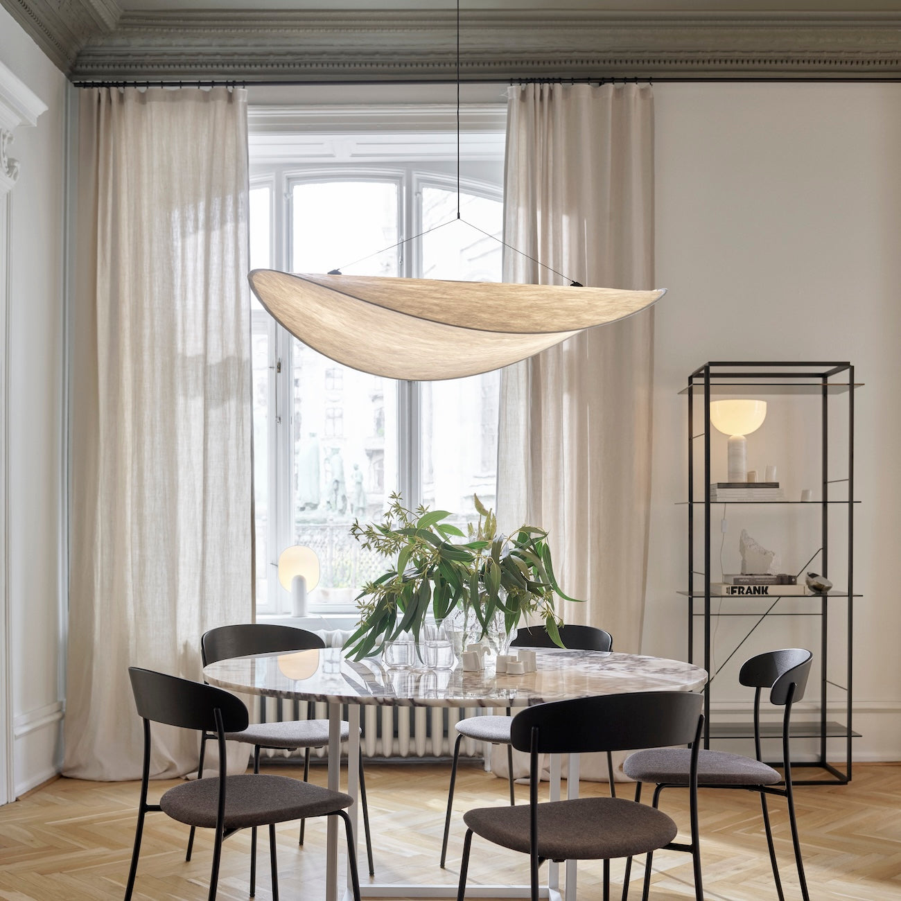Modern dining room with a round table, chairs, and a large window.