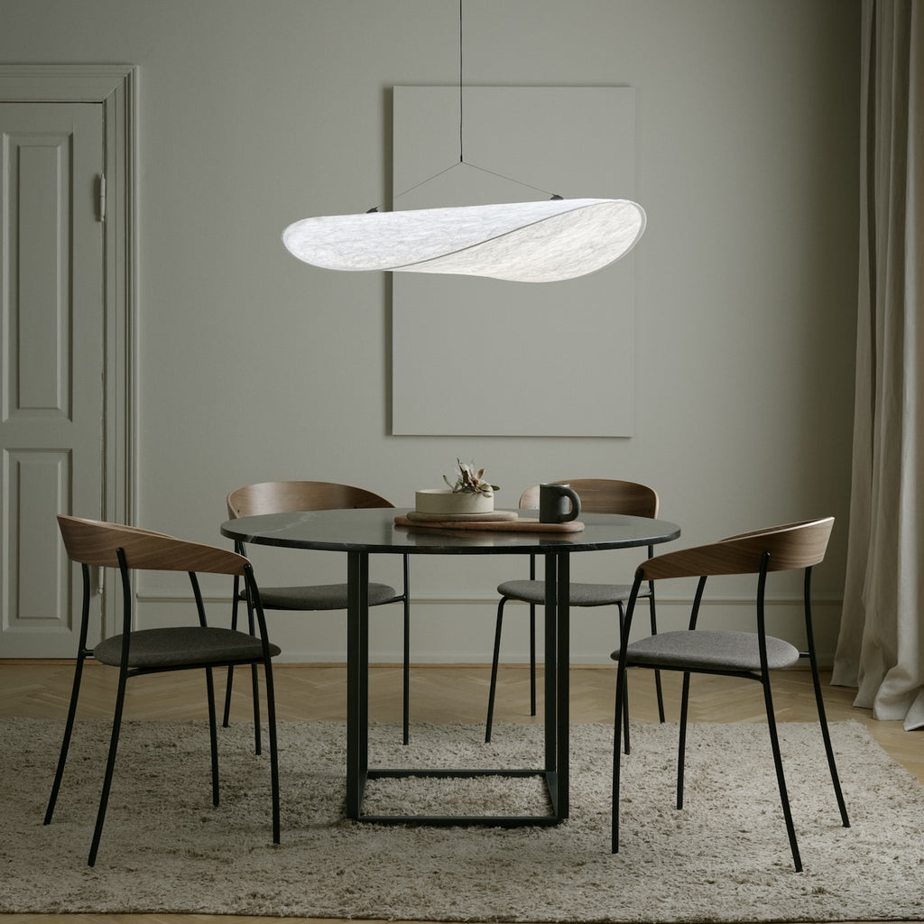 Dining room with a round table and chairs under a modern pendant light.