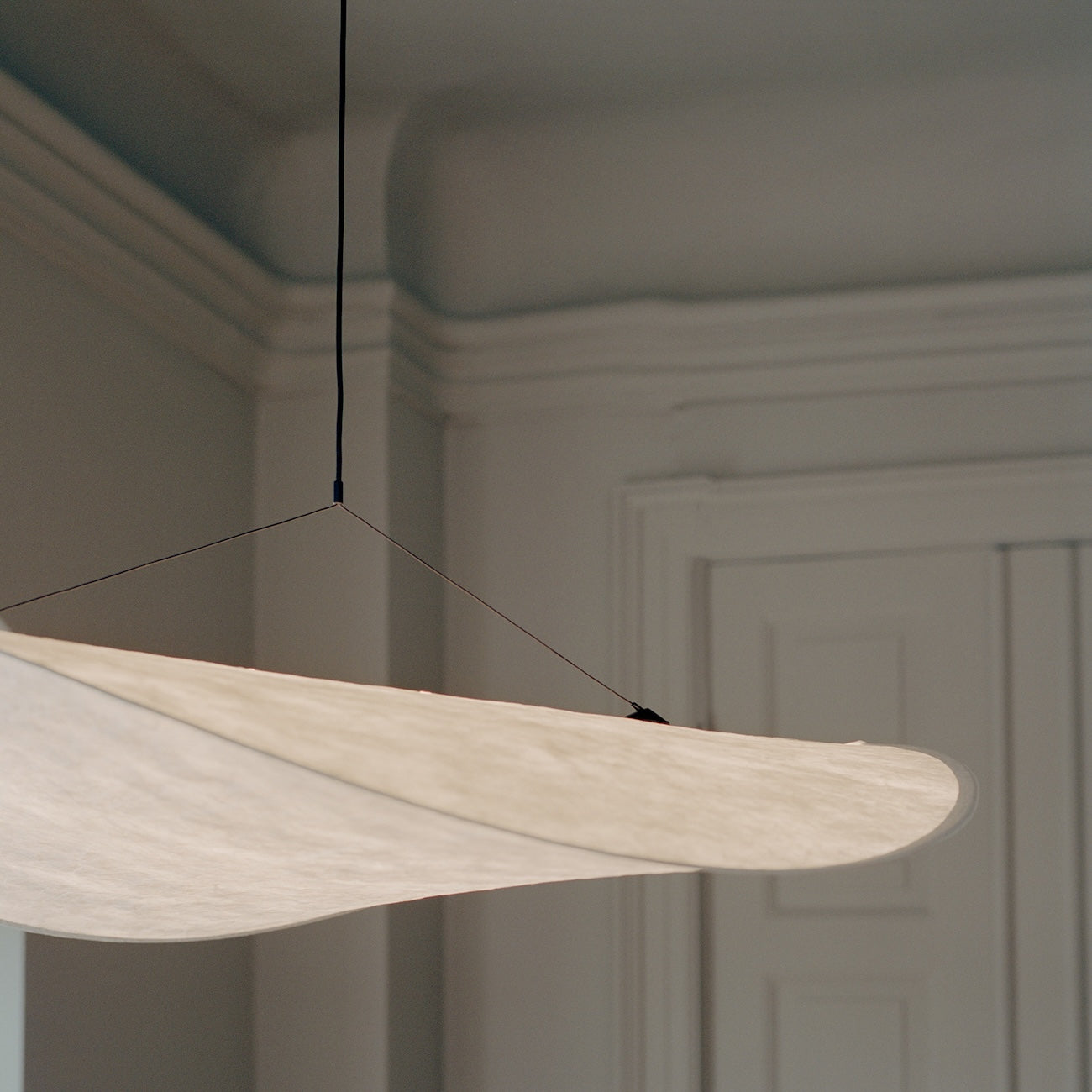 Modern pendant light fixture hanging in a room with neutral walls.