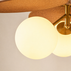 Close-up of a modern ceiling light fixture with two glowing frosted glass globe shades and a warm brass metal ceiling mount and canopy.